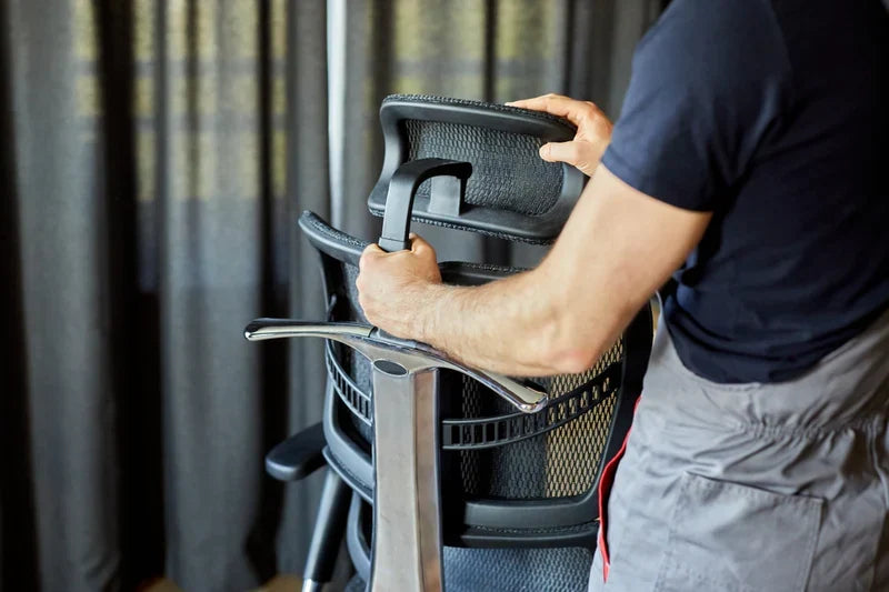 Persoana la birou pe scaun ergonomic, reglat pe statura ei